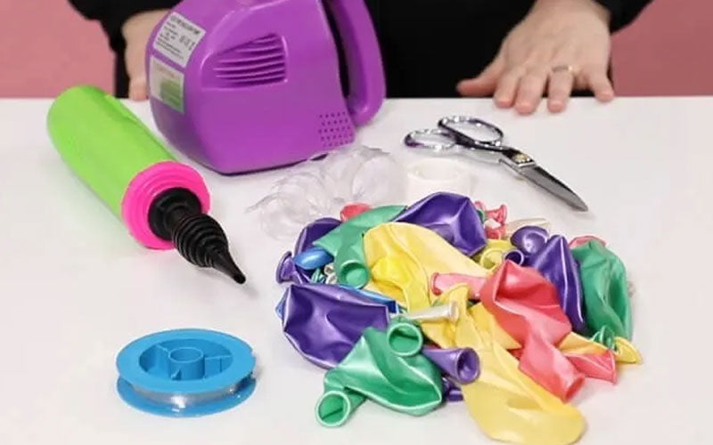 Balloons, pumps, scissors and tape ready for making a balloon arch