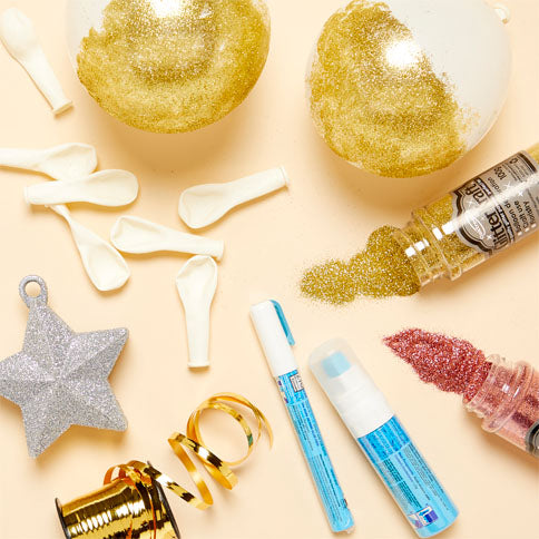 Gold balloons, confetti and decorating accessories arranged for a party display.