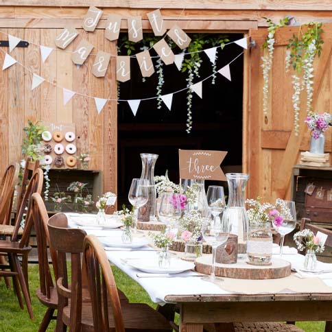 A rustic wedding table with wooden details, greenery and celebratory bunting.