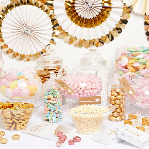 A pastel party sweet buffet with glass jars, treats and paper decorations.