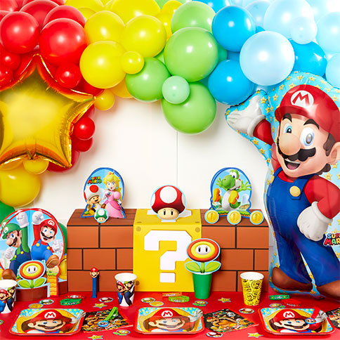 Super Mario birthday table with a Mario foil balloon, multicoloured balloons, plates and cups.