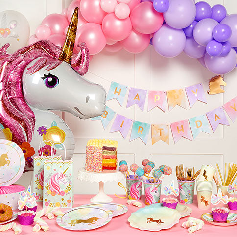 Unicorn party supplies arranged in a styled party setting.