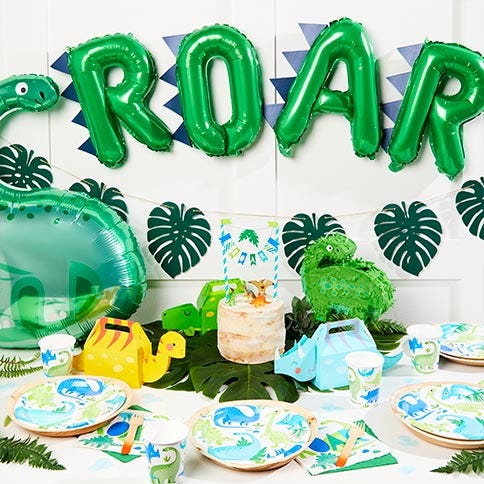 Dinosaur party supplies arranged in a styled party setting.