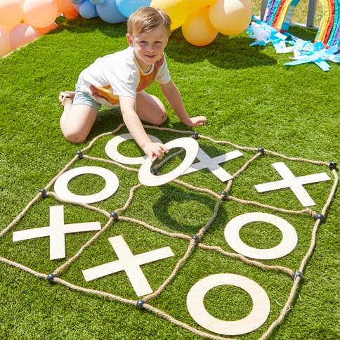 A child playing a giant noughts and crosses party game on the lawn.