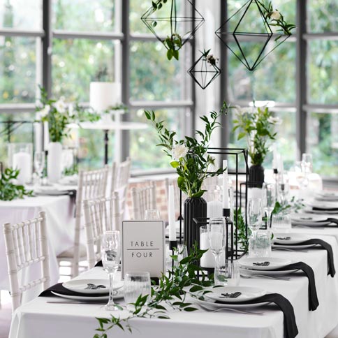 An elegant wedding table styled with white flowers, greenery and coordinated tableware.