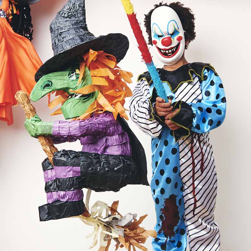 A child in fancy dress enjoying a Halloween piñata party game.