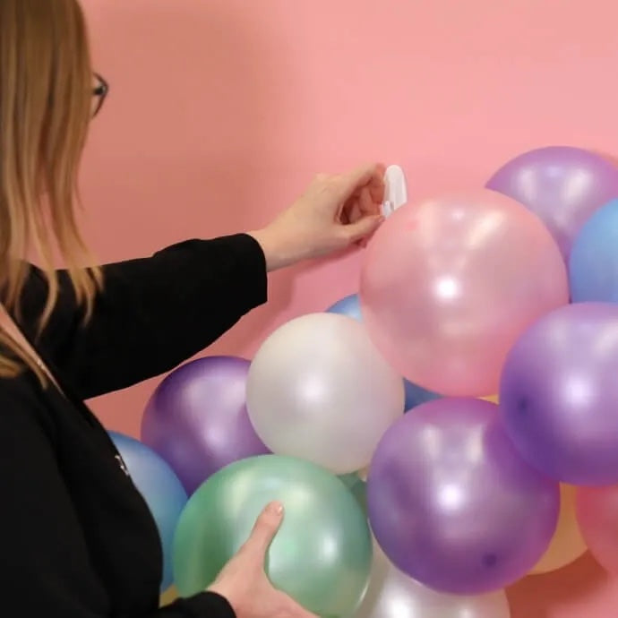 Balloon arch secured using removable wall hooks