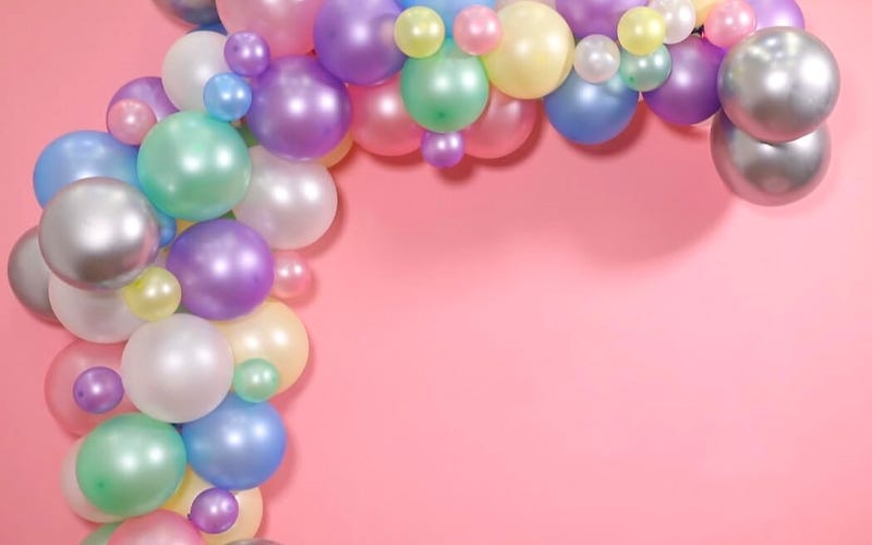 A large pastel pearlescent balloon arch pinned to a pink wall