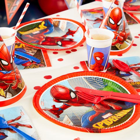 a spiderman party table with confetti, paper plates, cups and napkins